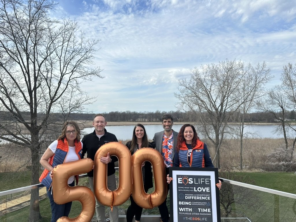 Daniel and an EOS client team celebrating his 500th session with balloons and The EOS Life sign